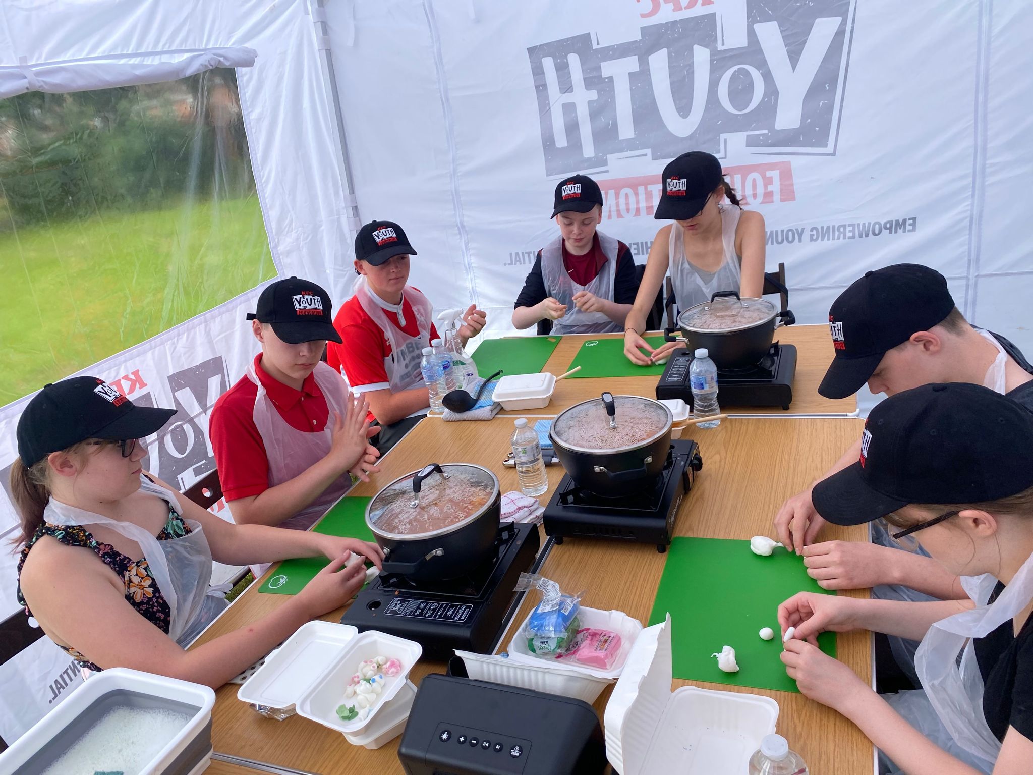 A group of children sat around a table preparing ingredients to cook with