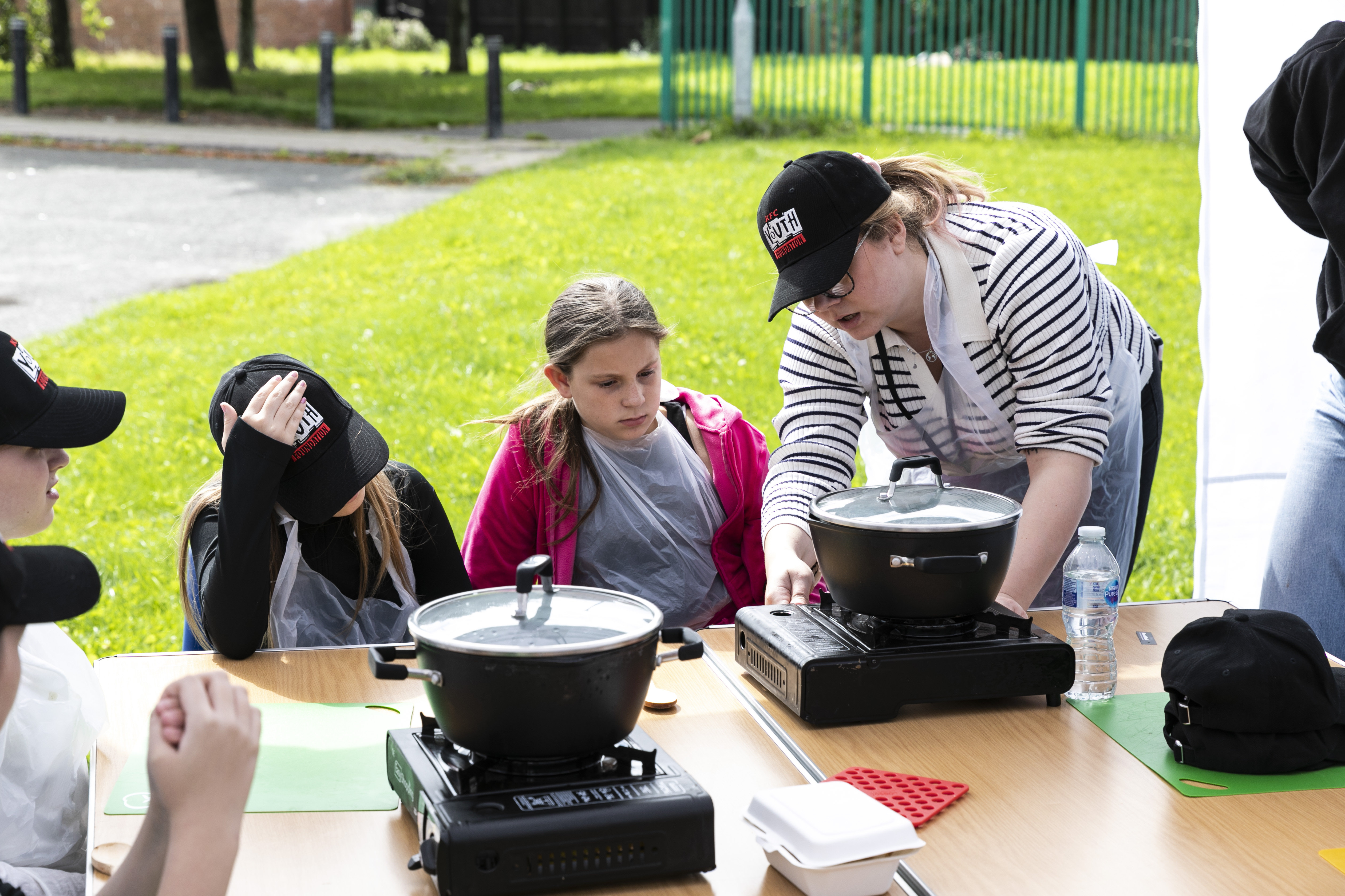 Young people with a youth worker turning on the portable hot plate and pot to cook