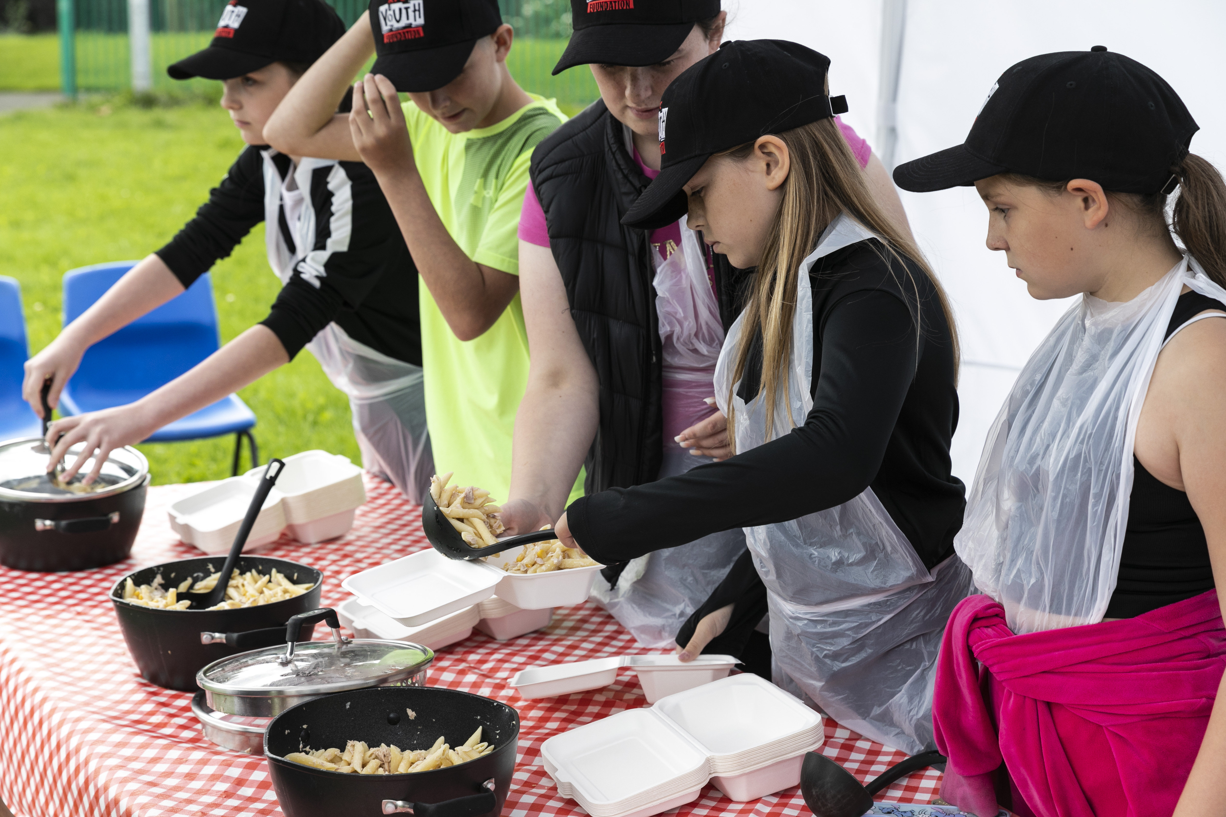 Four young people and a youth worker getting ready to serve the food they have prepared